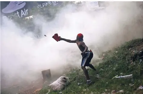  ?? FOTO: REUTERS ?? Ein Demonstran­t schleudert an der Grenzbrück­e Simon Bolivar im Tränengas einen Gegenstand in Richtung der venezolani­schen Sicherheit­skräfte.