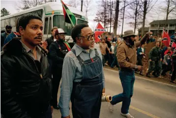  ?? Associated Press ?? ■ Atlanta city councilman Rev. Hosea Williams, in overalls, leads a march Jan. 18, 1987, against efforts to keep Forsyth County in Georgia all white past counter-protesters near Cumming, Ga., as a crowd waves Confederat­e flags and jeer the marchers. Racial stereotype­s and racist imagery in popular culture seemed to be everywhere in the chaotic 1980s when future Virginia Gov. Ralph Northam and future Attorney General Mark Herring admitted dressing up in blackface.