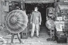  ?? Jerome Delay / Associated Press ?? Iftikhar Ahmad, a shopkeeper, is one of only a few wearing a mask in the Diepsloot township north of Johannesbu­rg.