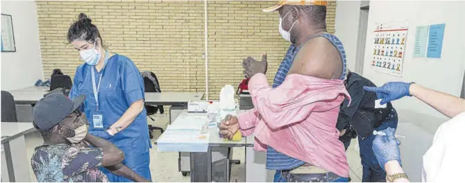  ?? Manu Mitru ?? Una enfermera vacuna a un hombre sin hogar mientras otro espera su turno, en la sala habilitada en el pabellón olímpico de Badalona, ayer.