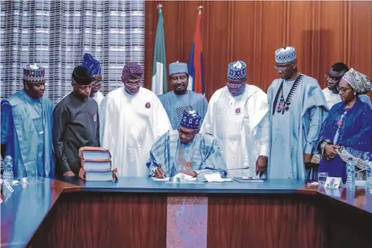  ??  ?? President Muhammadu Buhari signing the 2020 Budget in the presence of some senior officials of his administra­tion and leaders of the National Assembly