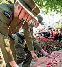  ??  ?? Servicemen lay poppies during the Anzac Day service at War Memorial Gardens.