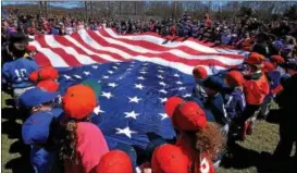  ?? BOB RAINES — DIGITAL FIRST MEDIA ?? Players stretch out a huge American flag on opening day of the Hatfield-Towamencin Little League season Saturday.