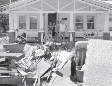  ?? EVAN VUCCI/AP ?? People sit outside their house during a visit by President Donald Trump to a neighborho­od impacted by Hurricane Florence Wednesday in New Bern, N.C. About 7,800 people remain in shelters in North Carolina, officials said.