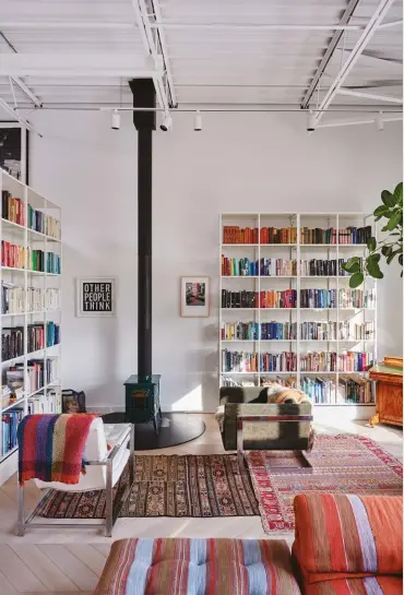  ??  ?? RIGHT The wood stove in the living room, from Vermont Castings, is surrounded by vintage rugs and armchairs bought in an East Jerusalem market, as well as a colourcode­d library.