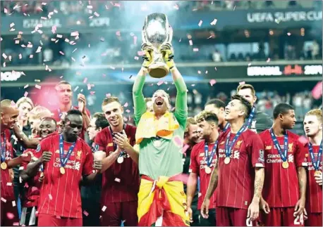  ?? OZAN KOSE/AFP ?? Liverpool goalkeeper Adrian holds the Uefa Super Cup trophy aloft as his teammates celebrate beating Chelsea on penalties at Besiktas Park Stadium in Istanbul on Wednesday.