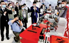  ?? PHOTOS BY ZHU XINGXIN / CHINA DAILY ?? Visitors are attracted to an intelligen­t robot writing Chinese characters at the fourth China Internatio­nal Import Expo on Nov 5 in Shanghai.