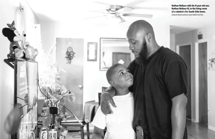  ?? ASHLEE REZIN GARCIA/SUN-TIMES PHOTOS ?? Nathan Wallace with his 8-year-old son, Nathan Wallace III, in the living room of a relative’s Far South Side home.