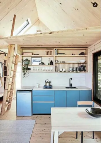  ?? ?? 2 Tucked beneath the mezzanine, the kitchen — with its solid-larch above-counter shelving and drying rack, reclaimed travertine worktops and blue-green cabinets — forms part of the open-plan living area.