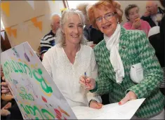  ??  ?? Aileen O’Reilly and Pat Cahillane signing Fr Enda’s card.