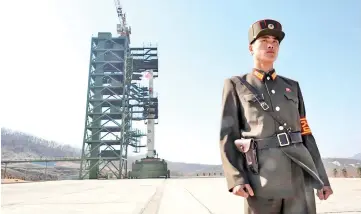  ??  ?? File photo shows a North Korean soldier standing guard in front of a Unha-3 rocket at the Sohae Satellite Launch Station in Tongchang-ri.