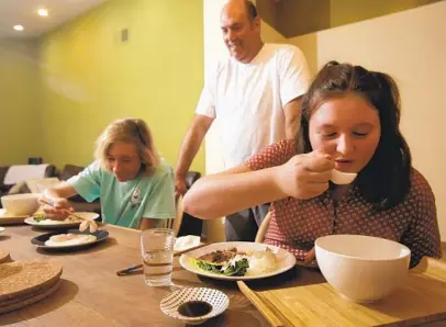  ?? BILL WECHTER ?? Rhyan Schwartz, 12, and her brother, Max, enjoy a Japanese meal prepared by their dad, executive chef Aron Schwartz, who has been making them gourmet lunches on breaks from online school.