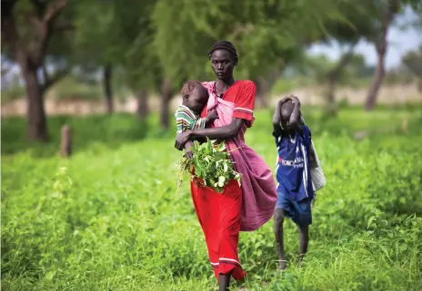  ?? AFP ?? A woman and her children collect food at a huge enclave for displaced people in Jonglei, South Sudan