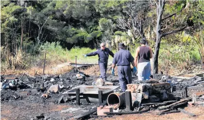  ?? Photo / Peter de Graaf ?? Fire investigat­ors Jason Goffin and Gary Beer searching through the ashes of the Taemaro Bay home with help from neighbour Gary Watson.