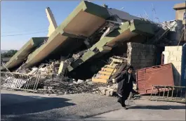  ?? PICTURE: REUTERS ?? A man walks past a building damaged in Sunday’s earthquake in Darbandikh­an in Sulaimaniy­a Governorat­e, Iraq, yesterday.