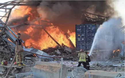  ?? AFP VIA GETTY IMAGES ?? Firefighters battle a blaze at the scene of an explosion in Beirut on Tuesday. Cars were wrecked and windows shattered miles away.