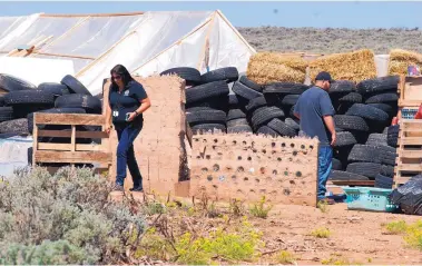  ?? MORGAN LEE/ASSOCIATED PRESS ?? Taos County officials survey the ramshackle compound near Amalia this week after sheriff’s deputies raided the encampment and found the body of a small child.