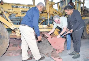  ?? CONTRIBUTE­D ?? Minister of Culture, Gender, Entertainm­ent and Sport Olivia Grange (right) examines a piece of the old turf at Stadium East as work got under way yesterday to remove the old track, which will be replaced by a new Regupol track. The track is scheduled to be ready for use before the end of February. Explaining to the minister the process for changing the track is Peter Breuer (centre), director of export, BSW, Germany, while Major Desmon Brown, general manager, Independen­ce Park Limited, looks on.