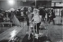  ?? PHOTO/LYNNE SLADKY] ?? A couple stands in line on Oct. 19 as rain falls on voters waiting for the precinct to open in Miami. Florida begins in-person early voting in much of the state Monday. With its 29 electoral votes, Florida is crucial to both candidates in order to win the White House. [AP