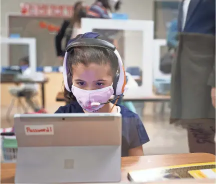  ?? JOE RONDONE/THE COMMERCIAL APPEAL ?? Students in Carol Welch’s kindergart­en class at Riverwood Elementary work inside desk partitions Monday as Shelby County Schools hold their first day of in-person learning since closing schools last March to safeguard staff and students from the COVID-19 pandemic.