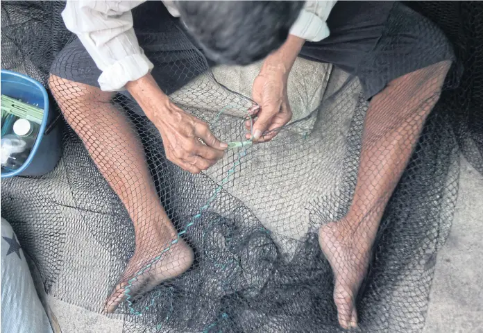  ??  ?? MANPOWER SHORTAGE: A Myanmar migrant worker prepares a net. The Phuket Fishing Associatio­n reported last year that local fisheries required over 2,000 migrant workers but only 1,200 were available.