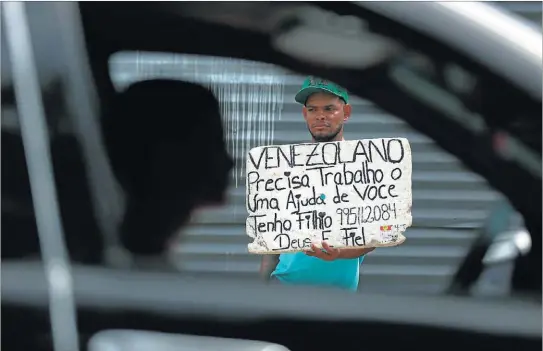  ?? BRUNO KELLY / REUTERS ?? El venezolano Denys Motaban posa con un cartel en portugués en el que pide trabajo y ayuda para su hijo, en Manaos (Brasil).