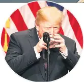  ??  ?? TAKING A TOT Trump holds glass like child