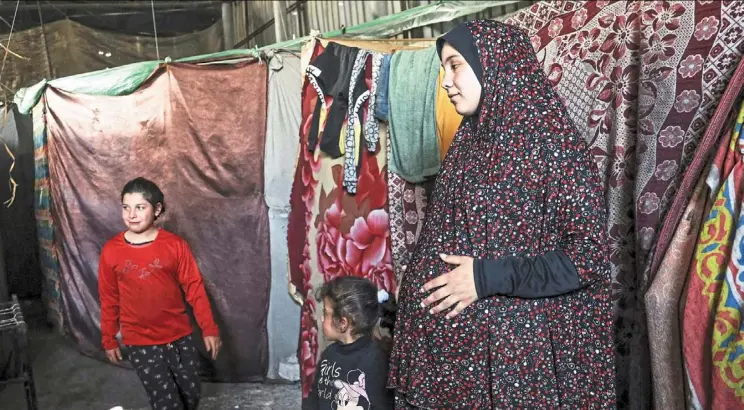  ?? — Photos: AFP ?? a pregnant Palestinia­n woman displaced from northern Gaza stands in a warehouse where she is taking shelter in rafah.