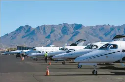  ?? ROSS D. FRANKLIN/AP ?? A staffer waits amid a row of jets Feb. 2 at Scottsdale Airport in Arizona. Traffic has increased at airports in the Phoenix area ahead of Sunday’s Super Bowl.