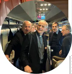  ?? In viaggio ?? Zuppi sul treno per Roma. Nella pagina a fianco l’anello cardinaliz­io (sopra) e uno striscione di CL per Zuppi