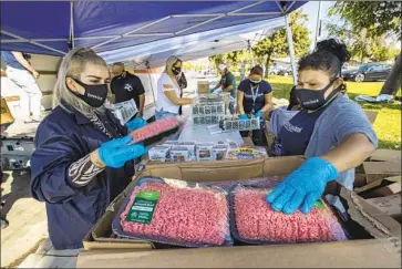  ?? MADELINE CANALES, Mel Melcon Los Angeles Times ?? left, and Edith Chacon of Homies Unidos pack ground beef into a box last month at Humphrey Park in Pacoima. Residents living around the park arrived with shopping carts and baby carriages.