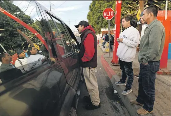  ?? Photograph­s by Gary Coronado Los Angeles Times ?? PABLO MAROQUIN, from El Salvador, approaches a car near the Benito Juarez Sports Center to inquire about day labor. The complex had been a migrant shelter.