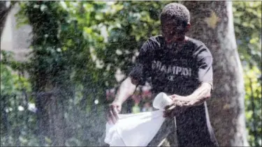  ?? MARY ALTAFFER — THE ASSOCIATED PRESS ?? A man uses a park sprinkler to cool off in New York. Dangerousl­y high heat in the Northeaste­rn United States has prompted emergency measures including extra breaks for players wilting at the U.S. Open tennis tournament.