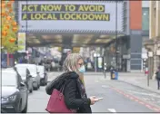  ?? PETER BYRNE— PA ?? A woman wearing a face mask walks in Manchester, England.