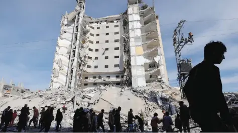  ?? — Reuters ?? Palestinia­ns gather near a building damaged in an Israeli air strike, in Rafah.