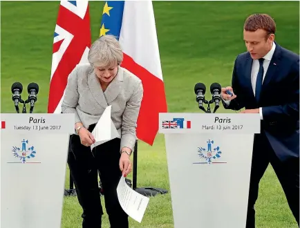  ?? PHOTO: REUTERS ?? French President Emmanuel Macron watches as Britain’s Prime Minister Theresa May recovers her speech notes after they blew away at the start of their joint media conference at the Elysee Palace in Paris.