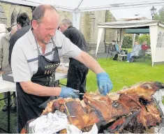  ??  ?? ●●Warren Robinson sorts out the hog roast to feed the hungry guests