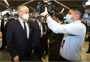  ?? — SAMUEL ONG/The Star ?? New normal, new platform:
Dr Wee being shown a thermal helmet during his walkabout at the Kuala Lumpur Internatio­nal Airport.