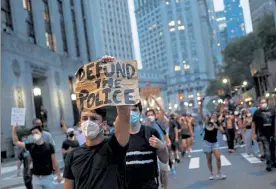  ?? JOHN MINCHILLO / AP ?? A demonstrat­or holds a sign that reads ‘Defund the Police’ during a protest march in support of the Black Lives Matter movement and other groups, in New York on July 30.