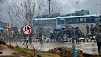  ?? AP ?? Paramilita­ry soldiers stand by the wreckage of a bus after the suicide attack in Pampore on Thursday. —