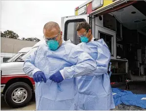  ??  ?? David Beranek (right) and Anthony Zajac put on protective gear before demonstrat­ing how paramedics will clean out their vehicles after transporti­ng a patient with coronaviru­s.
