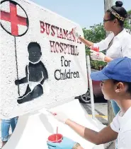  ?? PHOTOS BY NORMAN GRINDLEY/CHIEF PHOTO EDITOR ?? Kristina Hill (standing) and Krysan Burgher of Angels of Love paint the mural outside the Bustamante Hospital for Children in St Andrew.