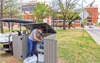  ?? CHRIS LANDSBERGE­R/THE OKLAHOMAN ?? Student Maria Melendez sets up the auto sampler to collect samples of public wastewater from the University of Oklahoma campus to have tested for the virus that causes COVID-19 in Norman on April 9.
