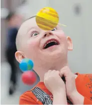  ?? PETER LEE WATERLOO REGION RECORD ?? Grayson Evans, 5, a senior kindergart­en student at Crestview Public School in Kitchener, marvels at a moving installati­on of coloured spheres representi­ng planets in a display illustrati­ng the solar system at a science fair at the school. Record photograph­er Peter Lee won a provincial newspaper award for the photo.