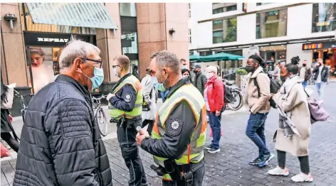  ?? RP-FOTOS (2): HANS-JÜRGEN BAUER ?? Kontrolle auf der Schadowstr­aße: André Blumenhofe­n (2.v.l.) und Enrico Niepelt (3.v.l.) informiere­n Passanten über die Maskenpfli­cht. Viele Bürger gingen auch gezielt auf die Ordnungskr­äfte zu, um sich über die neuen Regeln aufklären zu lassen.