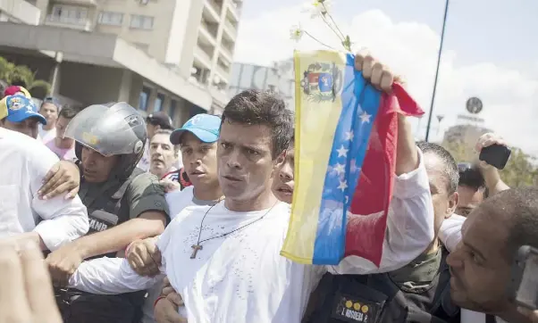  ??  ?? LEOPOLDO LÓPEZ muestra la bandera venezolana en el momento en que se entrega a miembros de la Guardia Nacional Bolivarian­a ayer en Caracas
