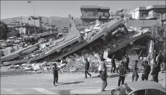  ?? AFP ?? People gather around a levelled building in the mountainou­s town of Darbandikh­an in Iraqi Kurdistan.