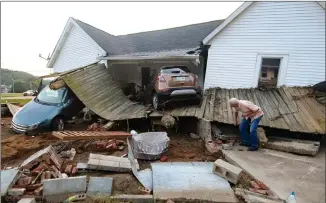  ??  ?? Ernest Hollis looks for items at his granddaugh­ter’s house that was devastated by the floodwater