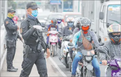  ?? Aaron Favila The Associated Press ?? Police operate a checkpoint Tuesday outside Manila, Philippine­s, as the capital was placed on lockdown in the hopes of controllin­g a surge of coronaviru­s cases. Most domestic flights to and from Manila were canceled, and night curfews will return in places.