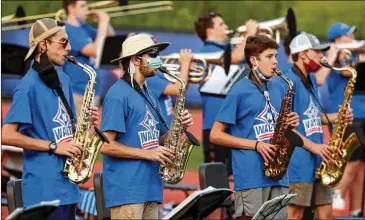  ?? PHOTOS BY JASON GETZ / FOR THE AJC ?? Masks and social distancing are strict requiremen­ts for members of high school marching bands while the pandemic continues to threaten the health and safety of students and their audiences.